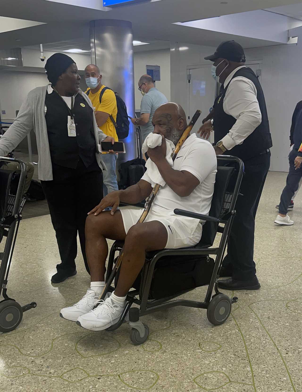 Mike Tyson, 56, pictured in wheelchair holding walking stick as fearsome boxing legend is pushed through Miami airport