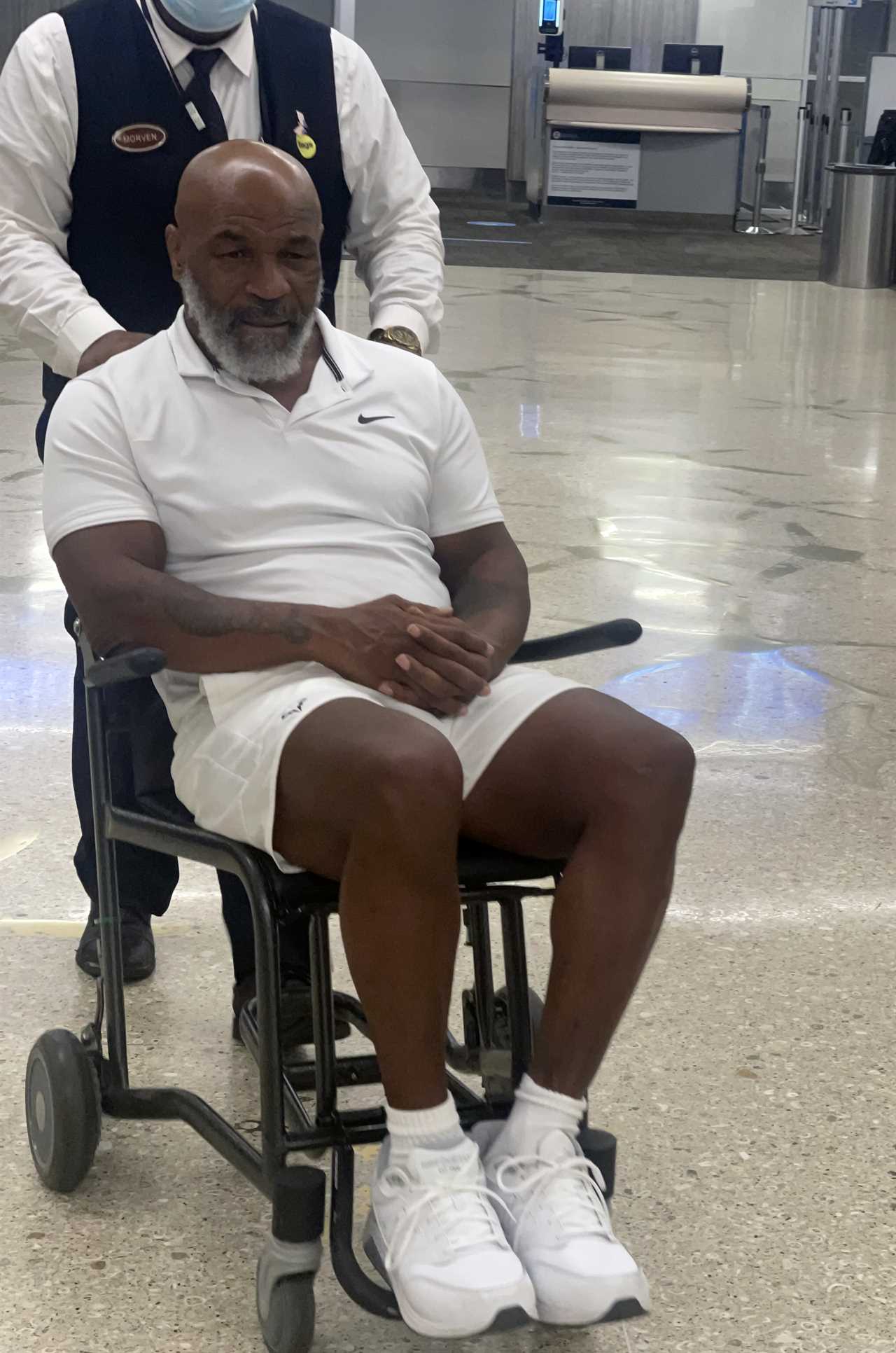 Mike Tyson, 56, pictured in wheelchair holding walking stick as fearsome boxing legend is pushed through Miami airport